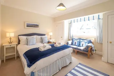 a bedroom with a bed with a blue blanket and a window at 12 Prevetts Way - Aldeburgh Coastal Cottages in Aldeburgh