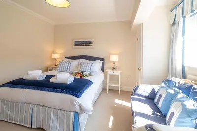 a bedroom with a large bed and a couch at 12 Prevetts Way - Aldeburgh Coastal Cottages in Aldeburgh
