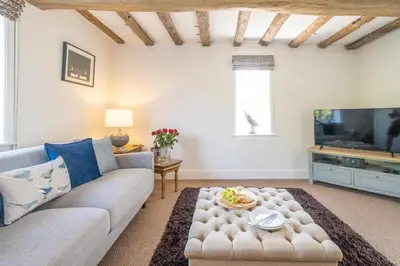 a living room with a couch and a tv at Laurel Cottage - Aldeburgh Coastal Cottages in Blyford