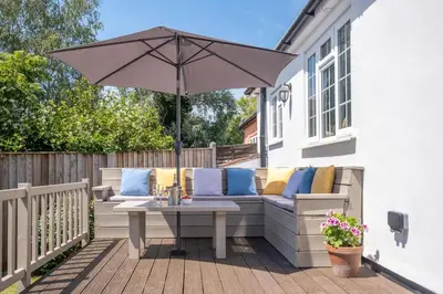 a patio with a table and an umbrella at Laurel Cottage - Aldeburgh Coastal Cottages in Blyford