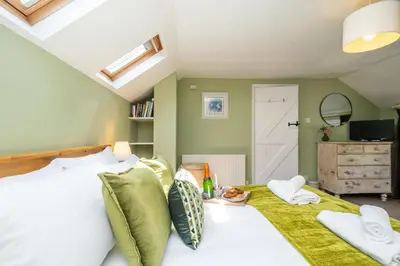a bedroom with a large bed with green walls at Laurel Cottage - Aldeburgh Coastal Cottages in Blyford