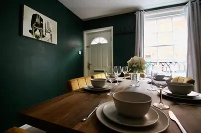 a dining room table with glasses and plates on it at West Street Retreat Grade II listed townhouse in Harwich