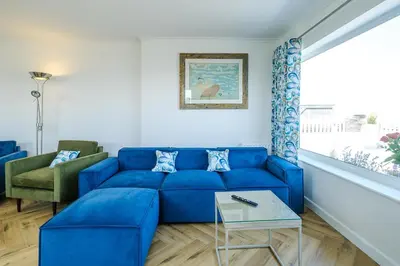 a blue couch in a living room with a window at Skippers Cottage - Aldeburgh Coastal Cottages in Aldeburgh