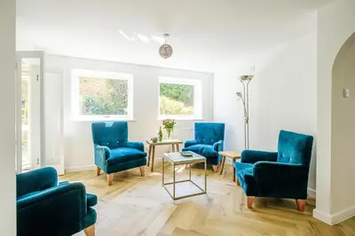 a living room with blue chairs and a table at Skippers Cottage - Aldeburgh Coastal Cottages in Aldeburgh