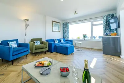 a living room with blue furniture and a bottle of wine at Skippers Cottage - Aldeburgh Coastal Cottages in Aldeburgh