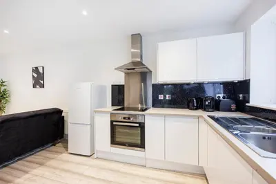 a kitchen with white cabinets and a sink and a refrigerator at Modern 1BR By Luxiety Stays Short Lets & Serviced Accommodation Southend on sea - City Centre, Nr the beach, High St & Adventure Island in Southend-on-Sea
