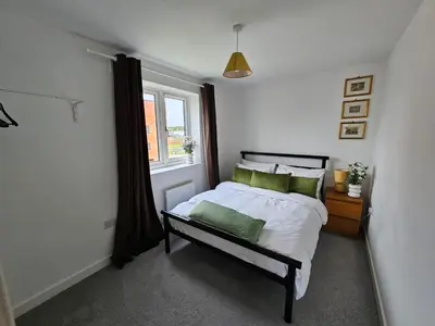 a bedroom with a bed with green pillows and a window at Modern 3 Bedroom Town House in Ipswich