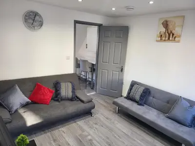 a living room with a couch and a clock on the wall at Vetrelax Colchester Three bedroom house- Sleeps up to 7 - Free Wi-Fi - Contractors - Families - Long Term Stays in Colchester