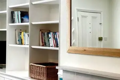 a mirror on the side of a wall with books at Charming 1 bed super central Terraced House in Cambridge