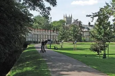 a person riding a bike down a road in a park at Charming 1 bed super central Terraced House in Cambridge