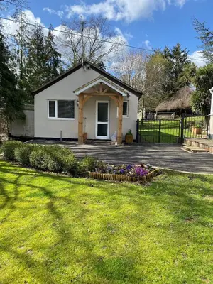 a white house with a fence and a yard at Chase Bungalow in Billericay
