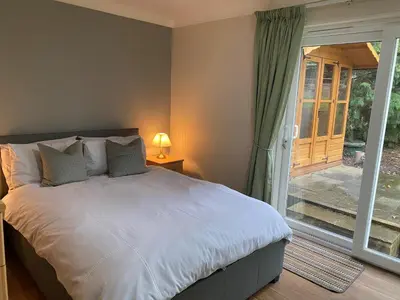 a bedroom with a bed and a sliding glass door at Chase Bungalow in Billericay