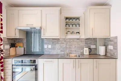 a kitchen with white cabinets and a sink at Hattie's, Great Glemham in Saxmundham