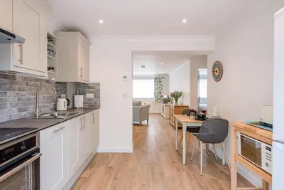 a kitchen with white cabinets and a dining room at Hattie's, Great Glemham in Saxmundham