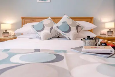 a bed with pillows and a tray with a book at Hattie's, Great Glemham in Saxmundham