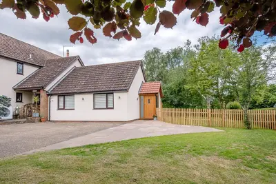 a white house with a wooden fence at Hattie's, Great Glemham in Saxmundham