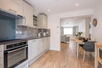 a kitchen with white cabinets and a dining room at Hattie's, Great Glemham in Saxmundham