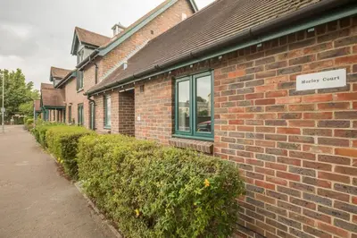 a brick building with a sign on the side of it at Lovely 1 Bed Apartment With FREE PARKING & Garden in Cherry Hinton