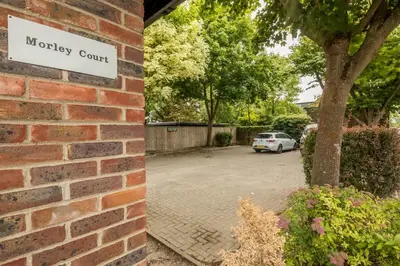 a brick wall with a driveway court sign on it at Lovely 1 Bed Apartment With FREE PARKING & Garden in Cherry Hinton