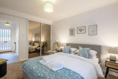 a bedroom with a large bed and a living room at Lovely 1 Bed Apartment With FREE PARKING & Garden in Cherry Hinton