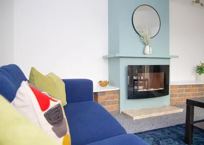 a living room with a blue couch and a fireplace at Parkside House Stevenage in Stevenage
