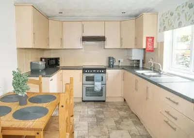a kitchen with a table and a stove top oven at Parkside House Stevenage in Stevenage