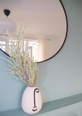 a vase with flowers in it next to a mirror at Parkside House Stevenage in Stevenage