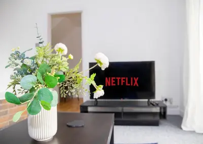 a living room with a tv and a vase with flowers at Parkside House Stevenage in Stevenage