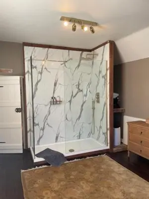 a bathroom with a shower with a marble wall at Blythe Cottage in Long Melford