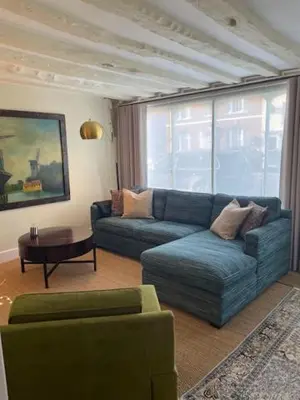 a living room with a blue couch and a table at Blythe Cottage in Long Melford