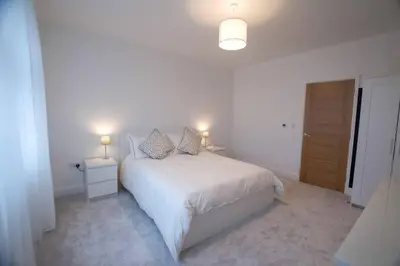 a white bedroom with a white bed and two lamps at New stylish 4 bed house moments from Clacton beach in Clacton-on-Sea