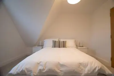 a bedroom with a white bed in a attic at New stylish 4 bed house moments from Clacton beach in Clacton-on-Sea