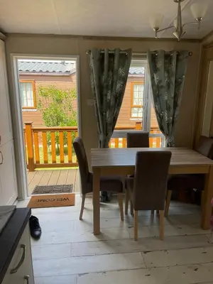 a dining room with a table and chairs and a balcony at Fern Lodge with Hot Tub in Stonham Aspall