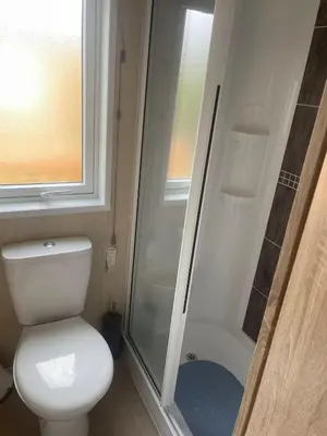 a small bathroom with a toilet and a shower at Fern Lodge with Hot Tub in Stonham Aspall