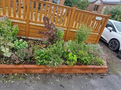 a garden with flowers in a wooden fence at Fern Lodge with Hot Tub in Stonham Aspall