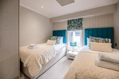 two beds in a bedroom with blue headboards at Briargate, Aldeburgh in Aldeburgh