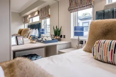 a bedroom with a bed and a desk and windows at Briargate, Aldeburgh in Aldeburgh