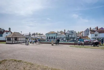 a group of people walking on a street with houses at Marshwiggle, Aldeburgh in Aldeburgh