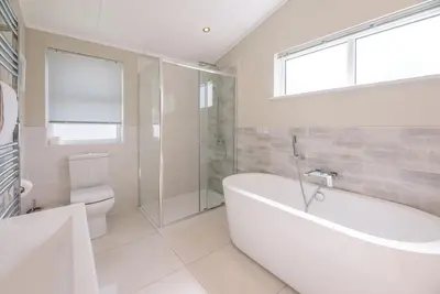 a white bathroom with a tub and a toilet at Marshwiggle, Aldeburgh in Aldeburgh