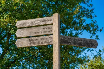 a wooden sign in front of some trees at Modern Studio with parking in shared garden in Theydon Bois
