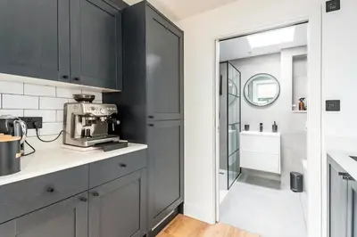 a kitchen with black cabinets and a counter top with a microwave at Modern Studio with parking in shared garden in Theydon Bois