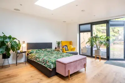 a bedroom with a large bed and a couch at Modern Studio with parking in shared garden in Theydon Bois