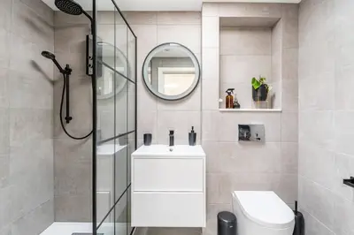 a bathroom with a shower and a sink and a mirror at Modern Studio with parking in shared garden in Theydon Bois