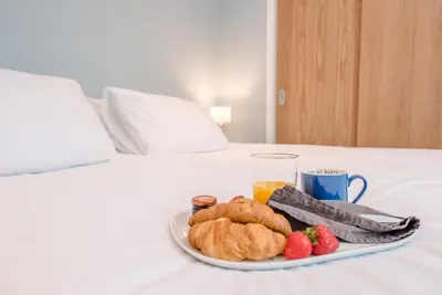 a plate of food with biscuits and strawberries on a bed at Ferry Corner Cottage, Sudbourne in Woodbridge