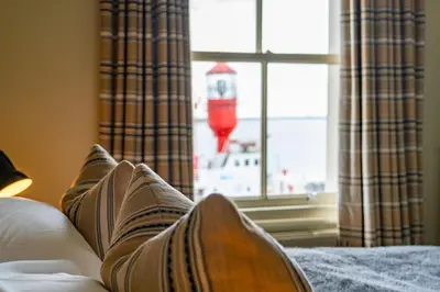 a person sitting on a bed looking out a window at The Pier Hotel in Harwich