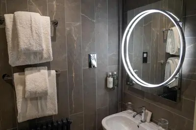 a bathroom with a sink and a mirror and towels at The Pier Hotel in Harwich