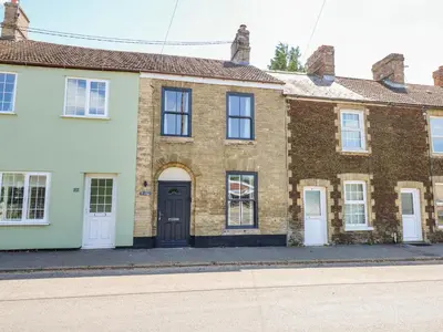 a brick house with a black door on a street at Lily Cottage in Downham Market