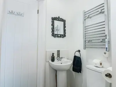 a white bathroom with a sink and a mirror at Lily Cottage in Downham Market