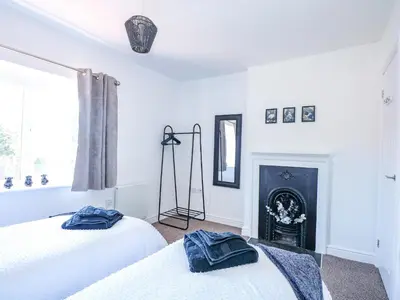 two beds in a white room with a fireplace at Lily Cottage in Downham Market
