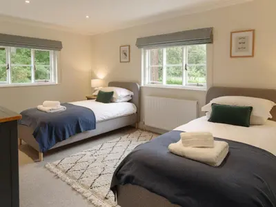 a bedroom with two beds and two windows at Garden House at Woodhall Estate in Hertford